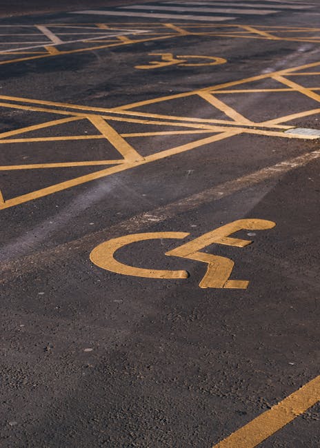 A row of four loading bays attached to a bright yellow warehouse or retail building, each bay labeled B56, B57, B58, and B59 with white signage. The bays feature black retractable shelters and metallic roll-up doors positioned at ground level, with a slightly overcast outdoor setting. The area in front of the bays is paved with parking spaces, some of which are marked with white lines. The image depicts the exterior environment likely used for delivery or removals services, with no vehicles or personnel visible. The clean, organized scene reflects the typical loading area for furniture transport or home relocation logistics, aligning with the services offered by Man with Van Tolworth, who may organize permits for such bays as indicated by the page title.